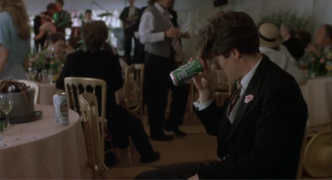 Four Weddings and a Funeral (1994) movie still: medium — A wedding reception tent filled with guests seated at round tables under white fabric. A…
