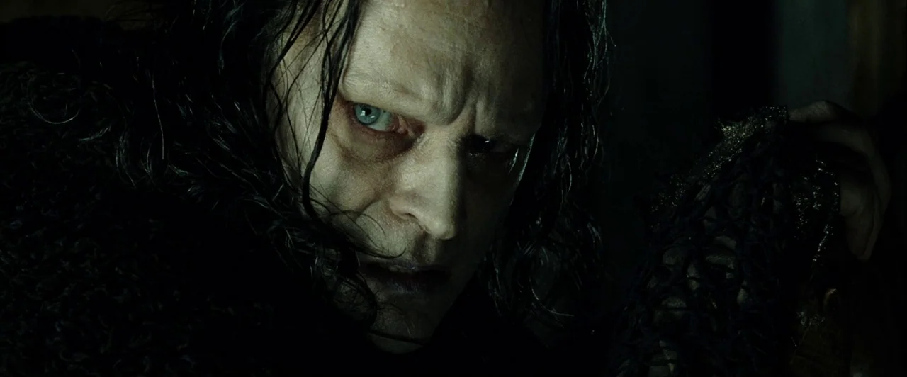 The Lord of The Rings: The Two Towers (2002) movie still: closeup — A dimly lit enclosed space with deep shadows surrounding the subject. A pale man…