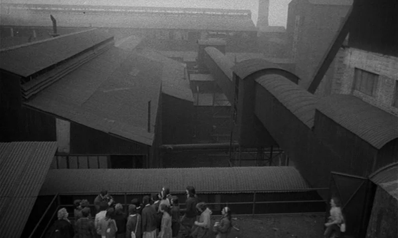 Man Is Not Bird (1965) movie still: establishing — A vast, sprawling industrial complex features interconnected metal buildings and elevated…