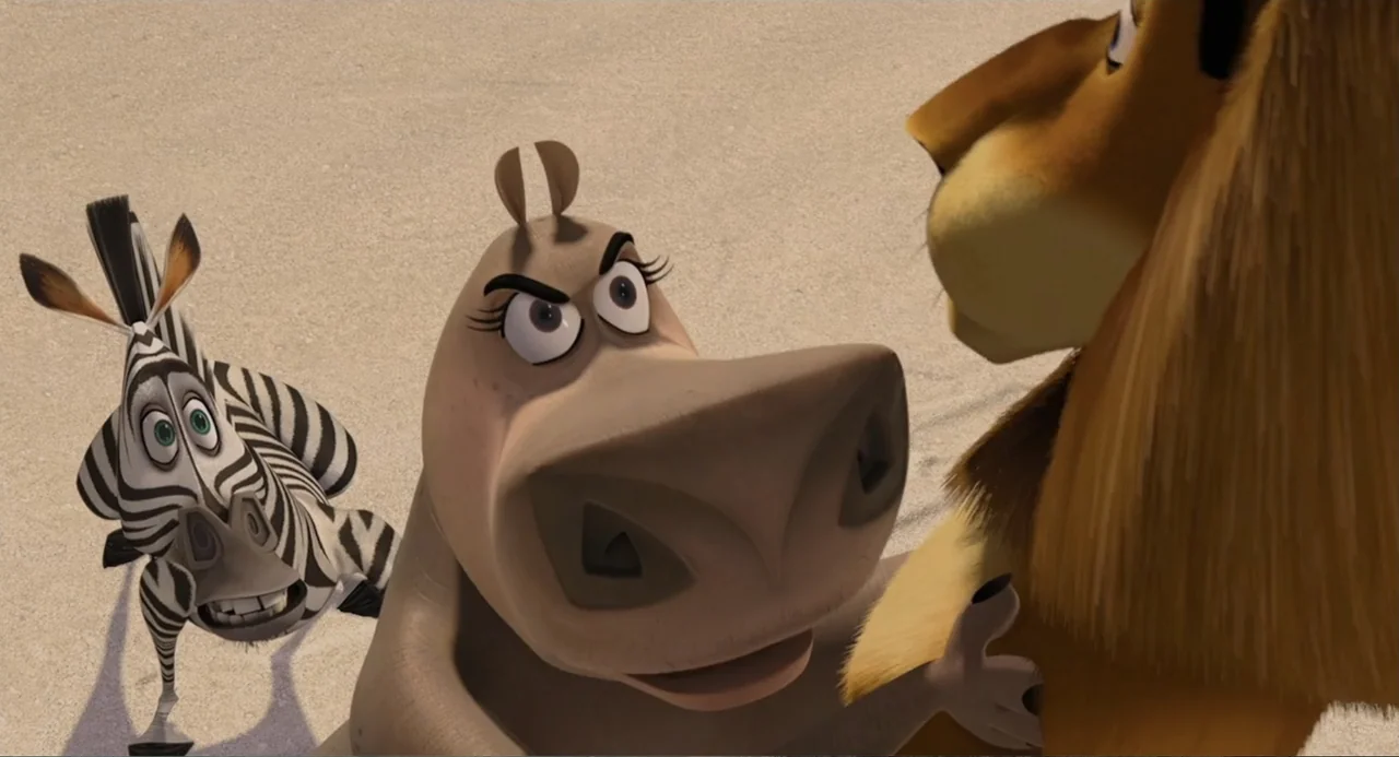 Madagascar (2005) movie still: medium — A wide expanse of open sandy terrain provides the backdrop for three animals. A hippo sits facing a lion…