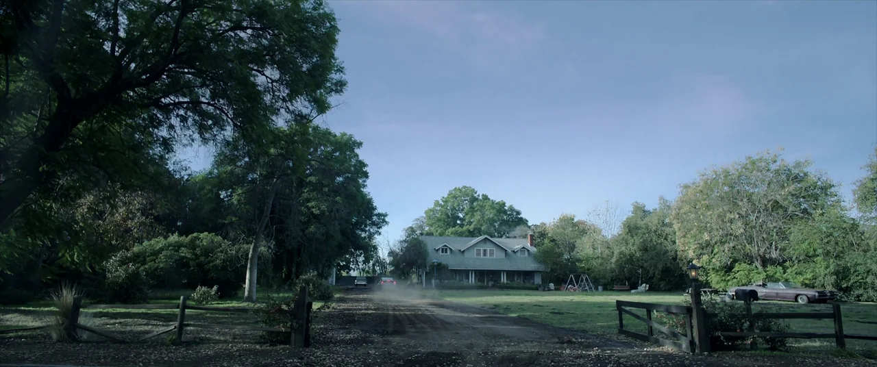 Malignant (2021) movie still: establishing — A quiet rural house sits at the end of a long, dusty dirt driveway. Mature trees surround the property,…