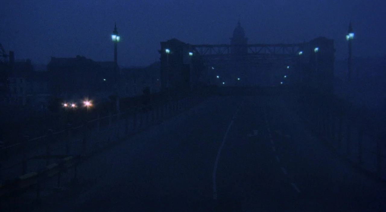 The Iguana with the Tongue of Fire (1971) movie still: establishing — A dark, empty suspension bridge spans across the frame under a deep blue night…