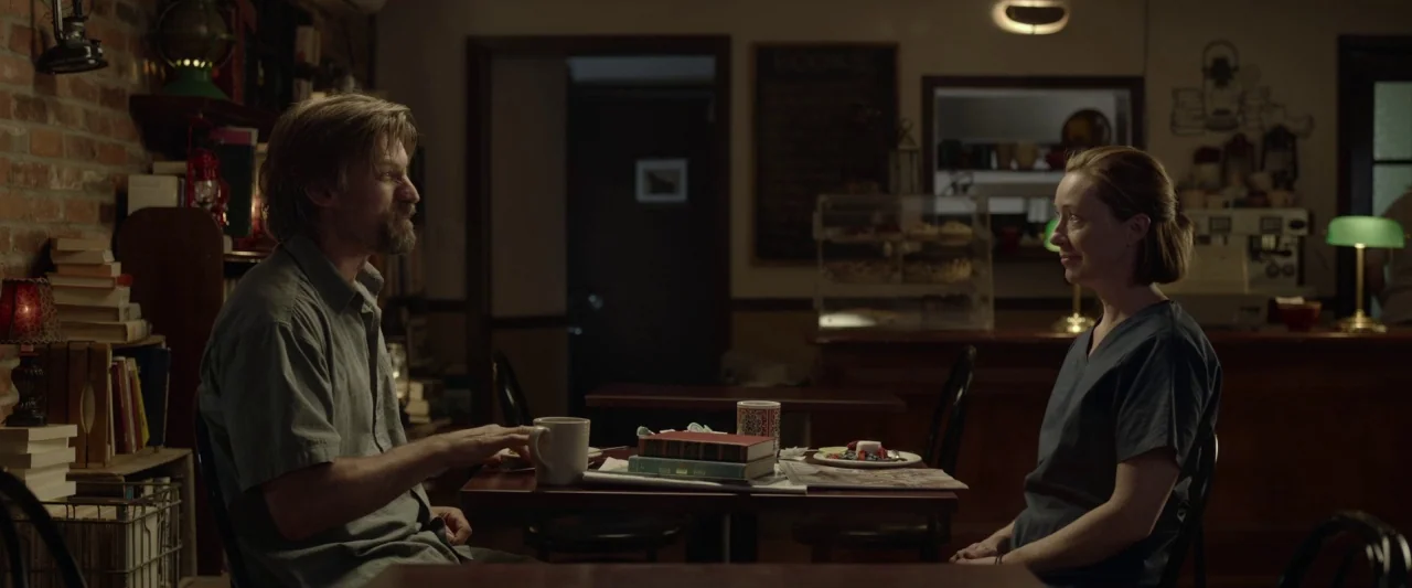 Small Crimes (2017) movie still: medium — A dimly lit, rustic interior space with exposed brick walls and various vintage lanterns. A man and a…
