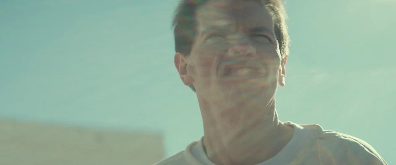 Halloween (2018) (2018) movie still: closeup — A man stands outdoors under a bright, cloudless sky during the daytime. The subject looks upward…