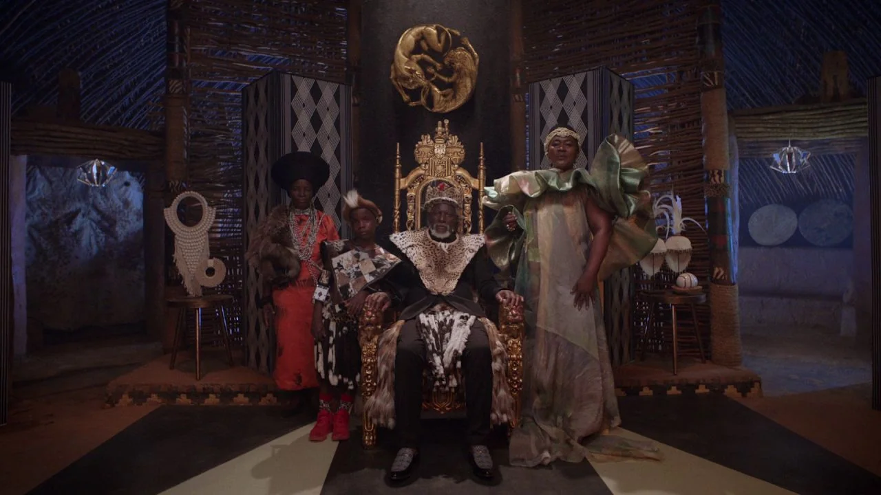 Black is King (2020) movie still: fullbody — A circular room constructed with wooden lattice walls and decorative geometric patterns. Four figures…