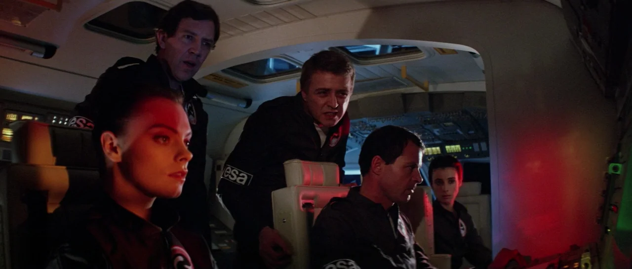 Lifeforce (1985) movie still: medium — The interior of a cramped spacecraft cockpit features dim lighting and glowing instrument displays. Five crew…