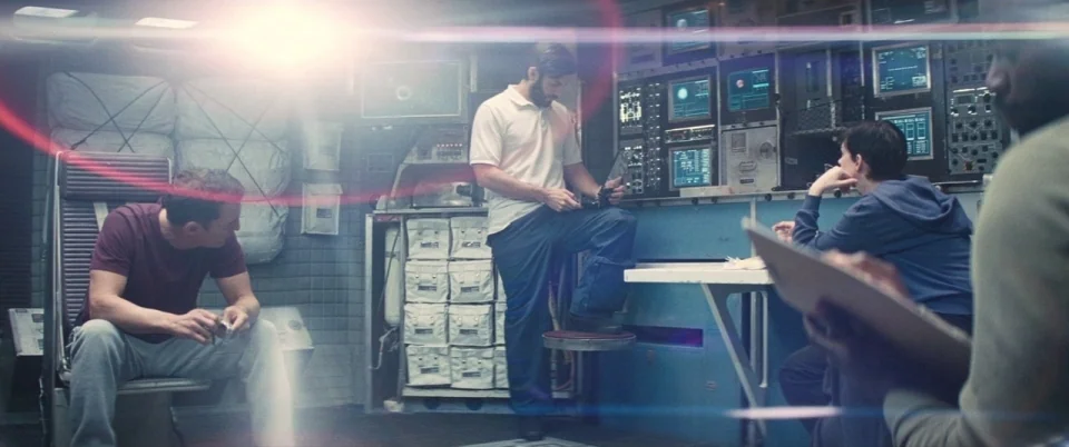 Interstellar (2014) movie still: wide — A utilitarian spaceship interior with multiple control panels and stacked storage modules. Three men occupy…
