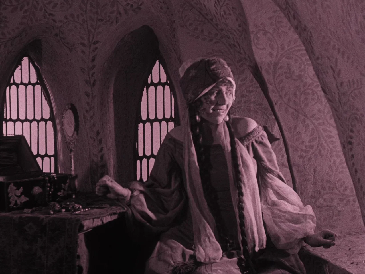 The Golem (1920) movie still: medium — A stone room features vaulted ceilings with painted leaf patterns and two arched windows. A young woman in a…