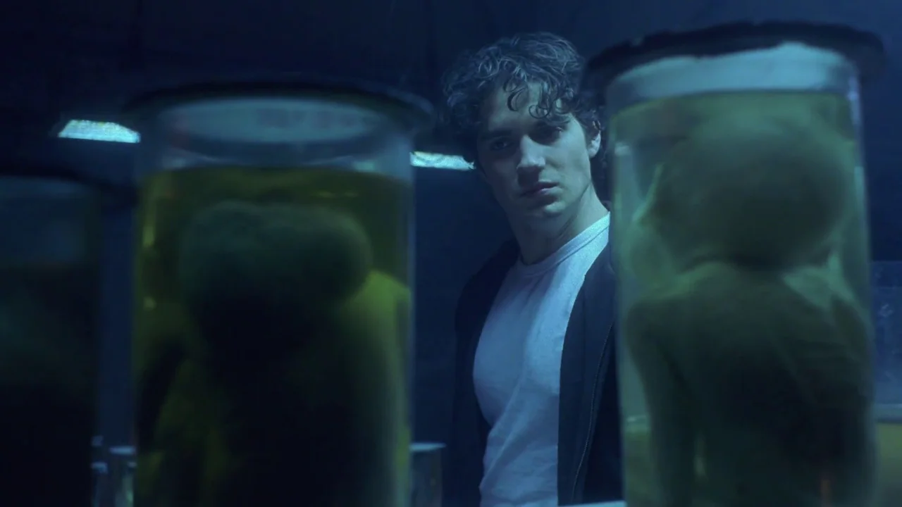 Hellraiser: Hellworld (2005) movie still: medium — A dark laboratory features multiple glass specimen jars filled with murky yellow liquid. A young…