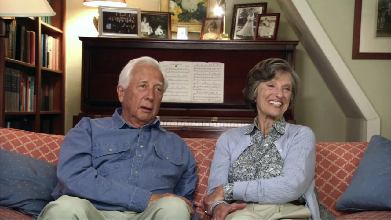 David McCullough: Painting with Words (2008) movie still: medium — An interior living room features a wooden piano and framed photos on a shelf. An…