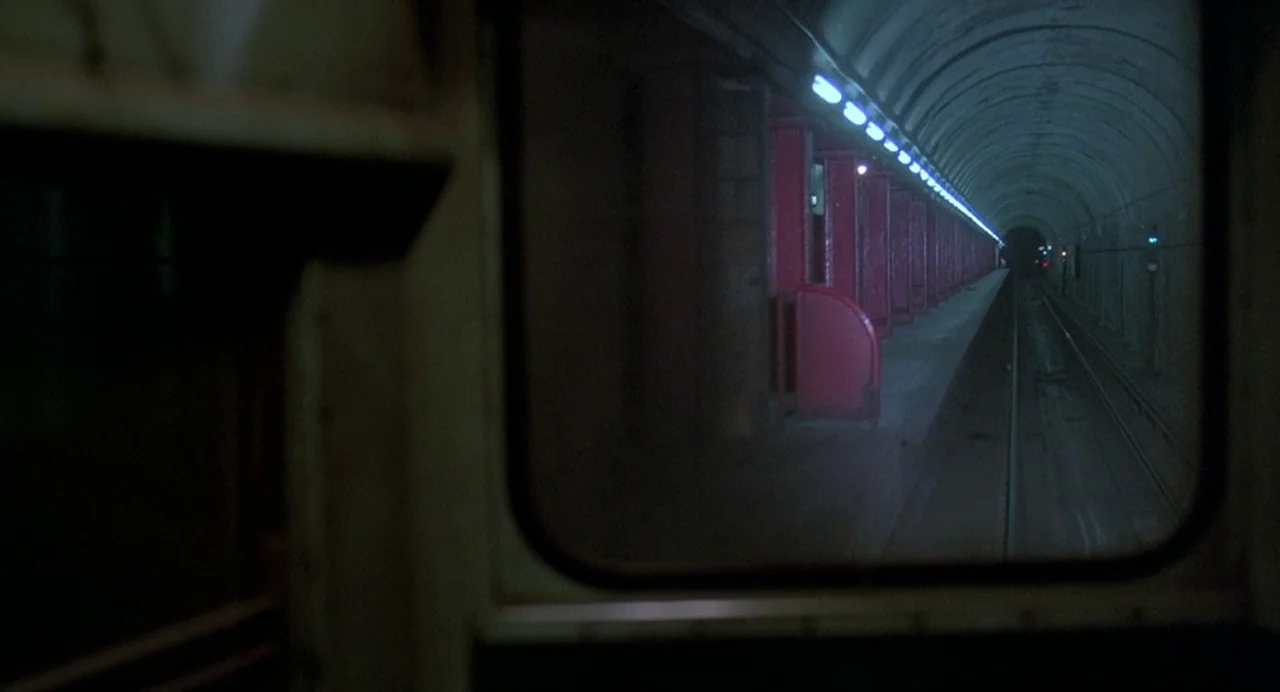Streets of Fire (1984) movie still: establishing — A dark subterranean subway tunnel features arched ceilings and red support pillars. A train…