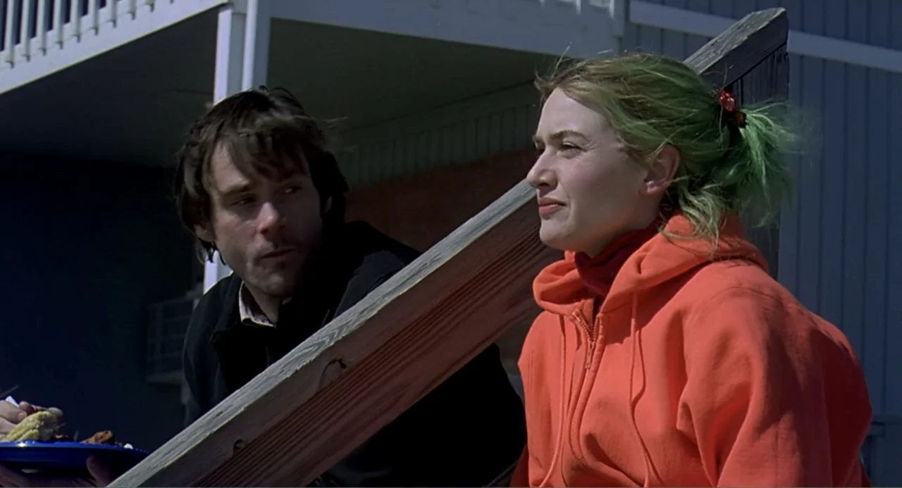 Eternal Sunshine of the Spotless Mind (2004) movie still: medium — A wooden deck attached to a blue building sits under bright natural light. A…