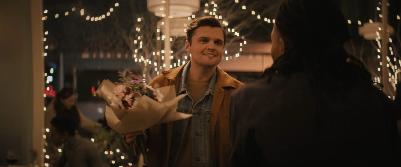 Something from Tiffany's (2022) movie still: medium — A dimly lit restaurant interior features blurred strings of warm white decorative lights.