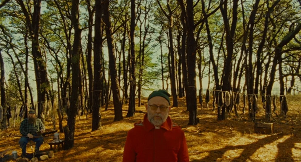 Moonrise Kingdom (2012) movie still: medium — A dense woodland clearing contains numerous animal pelts hanging from a clothesline between trees. A…