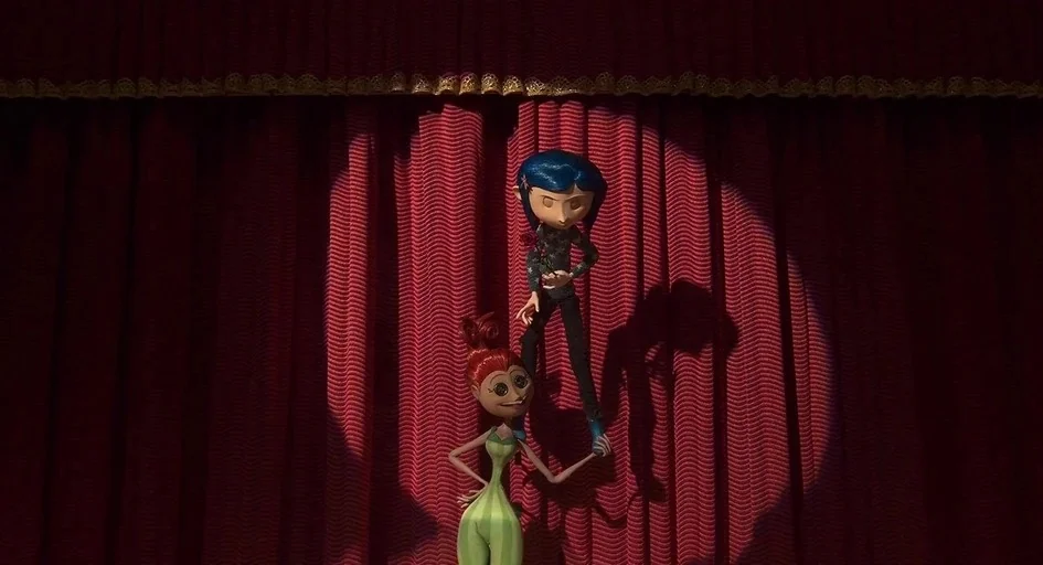 Coraline (2009) movie still: fullbody — A dark stage features deep red heavy curtains textured with vertical folds. Two stop-motion figures stand…