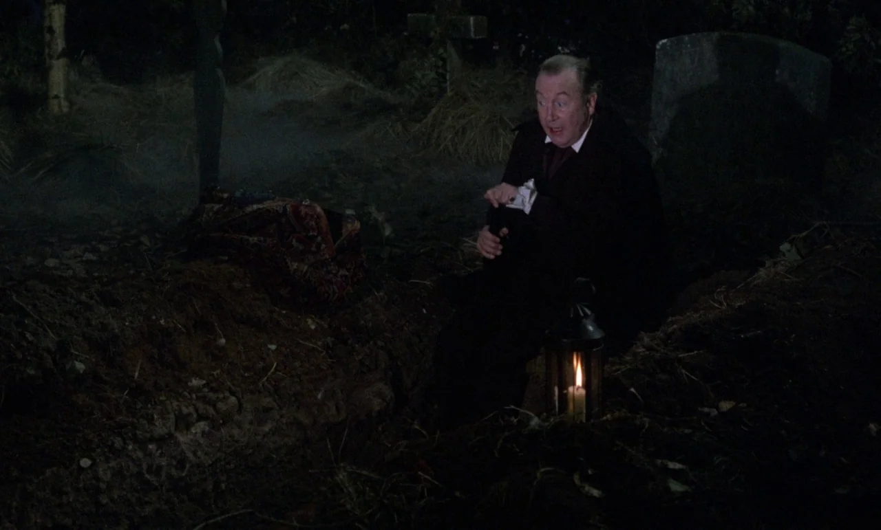 The Horror of Frankenstein (1970) movie still: medium — A dark graveyard at night is covered in patches of low-lying fog and dirt. An older man in…