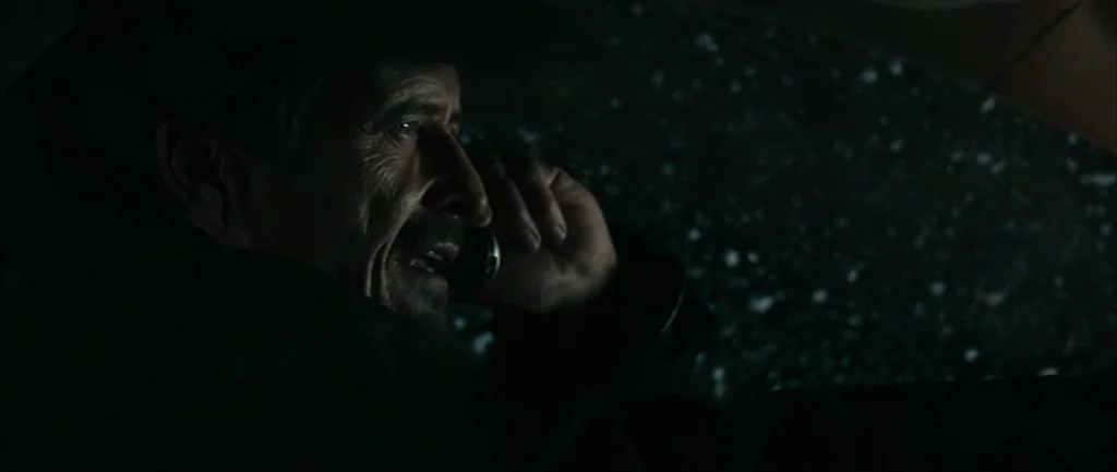 Pontypool (2008) movie still: closeup — A man sits inside a dark vehicle at night during a rainstorm. He speaks on a cell phone while glancing out…