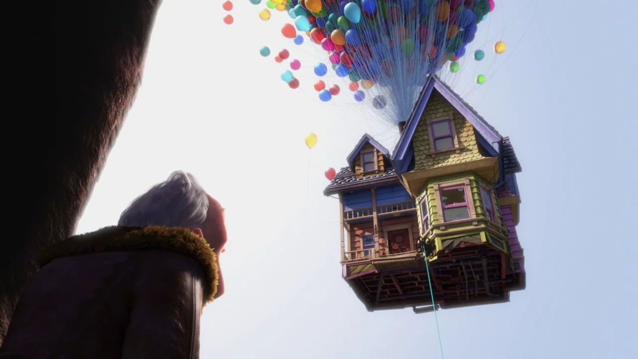 Up (2009) movie still: wide — An elderly man looks up at a wooden house floating in the clear sky. The house is held aloft by a massive cluster of…