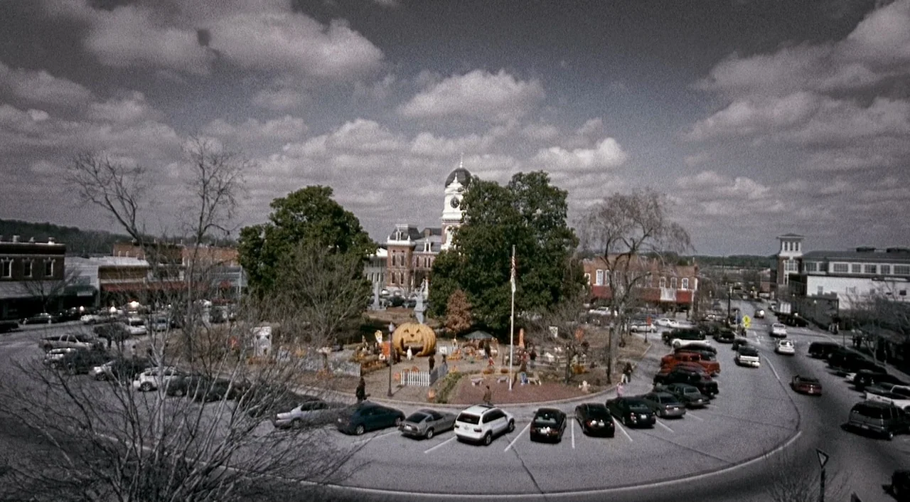 Halloween 2 (2009) movie still: establishing — A high-angle view of a town square featuring a courthouse building in the distance. The center…