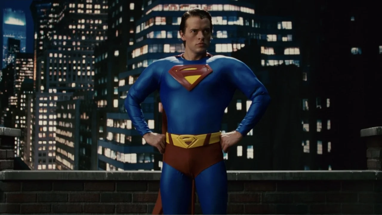 Epic Movie (2007) movie still: medium — A man dressed as Superman stands on a brick ledge overlooking a city. The background shows illuminated…