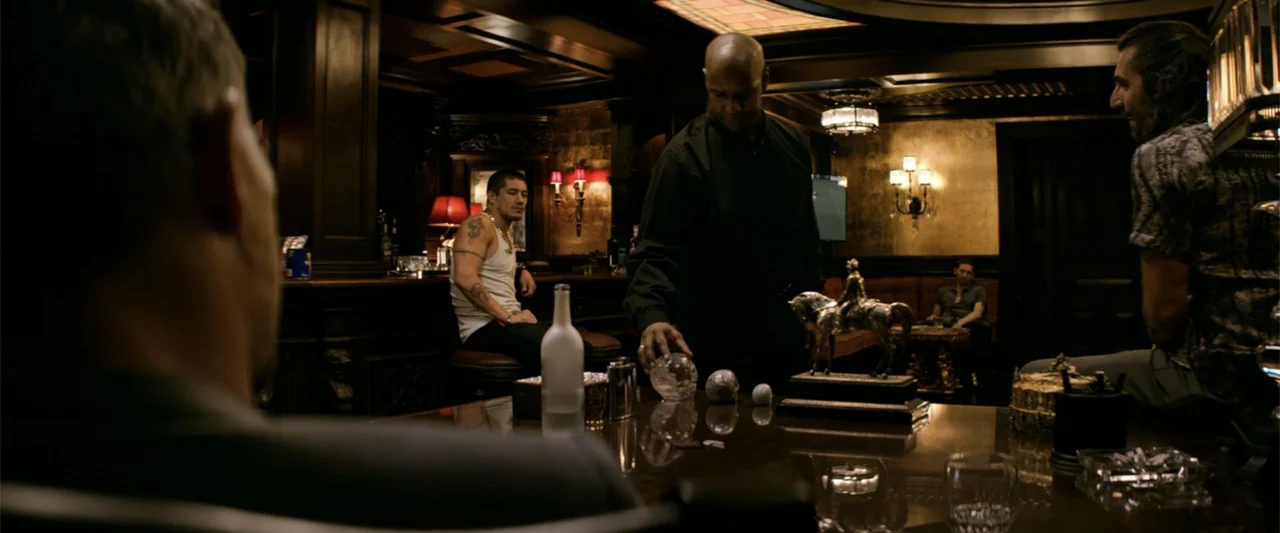 The Equalizer (2014) movie still: medium — A dimly lit, wood-paneled room features a large polished table and leather upholstery. A man stands at…