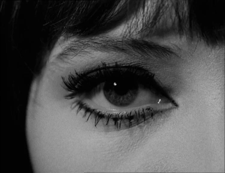 Alphaville (1965) movie still: closeup — A extreme close-up focuses entirely on a human eye with heavy dark makeup. The surrounding skin and hair…