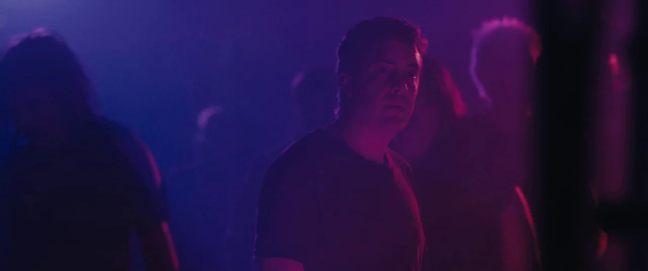 Blue Ruin (2013) movie still: medium — A dimly lit, crowded venue features dense haze and intense colored lighting. A man stands in the foreground…