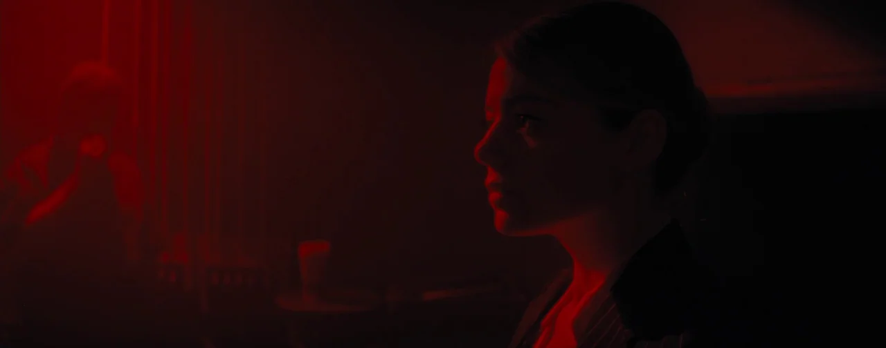 La La Land (2016) movie still: medium — A dark space is filled with intense red light. A woman stands in profile looking to the left.