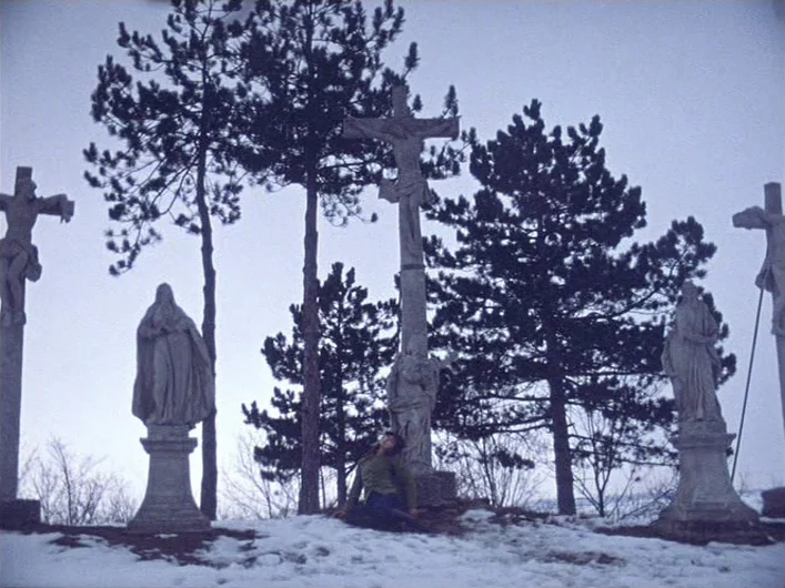 The Death of Maria Malibran (1972) movie still: wide — A snowy hilltop contains multiple stone crucifix statues interspersed with dark evergreen…