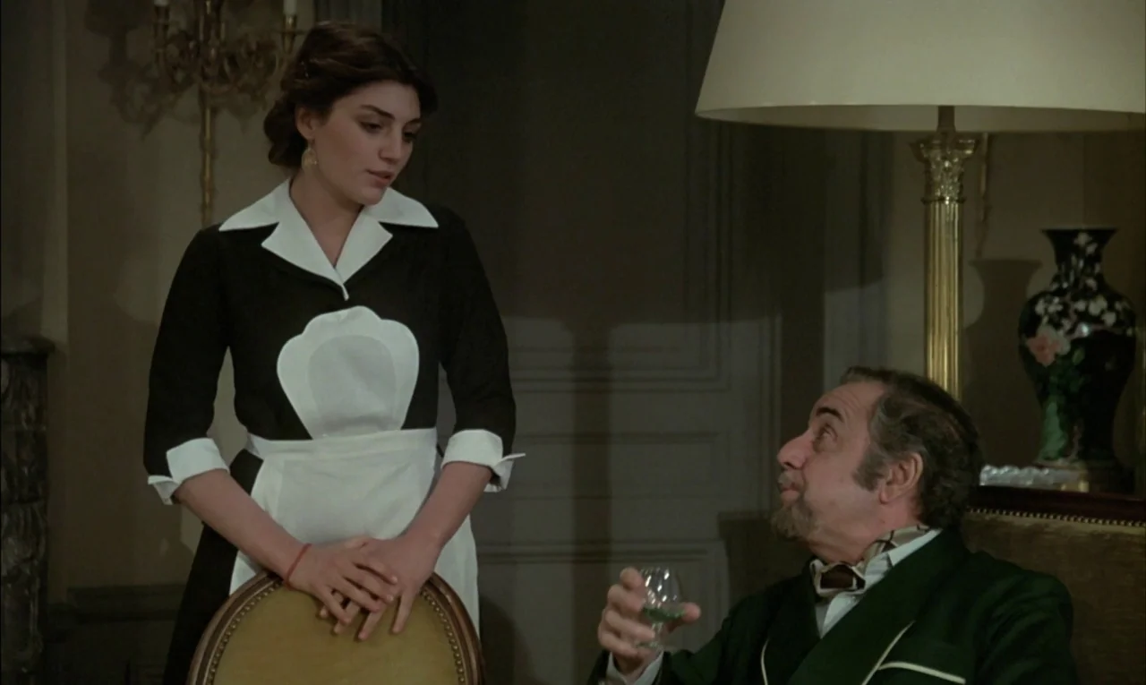 That Obscure Object of Desire (1977) movie still: medium — A dimly lit room features a formal sitting area with antique furniture and decor. A young…