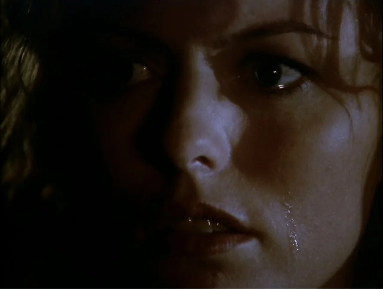 At the Midnight Hour (1995) movie still: closeup — A dimly lit interior space with deep shadows obscuring most of the background environment. A…