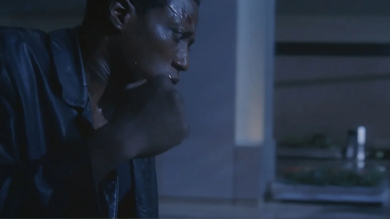 The Art of War (2000) movie still: medium — A dark apartment interior with blurred household surfaces in the soft focus background. A man wearing a…