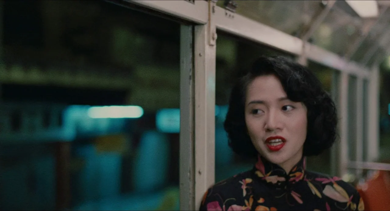 Rouge (1987) movie still: medium — An interior of a bus at night with blurred city lights through the window. A young woman with red lips wearing a…