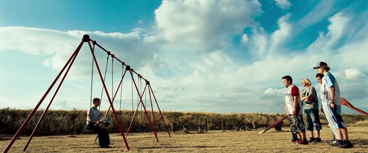 Harry Potter & The Order of the Phoenix (2007) movie still: wide — A dry, grassy playground contains a set of red metal swings under a cloud-filled…