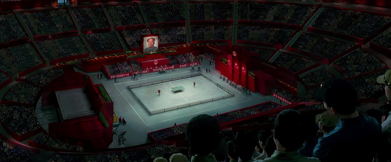 Forrest Gump (1994) movie still: establishing — A massive indoor arena decorated in deep red features a central illuminated table tennis court. A…