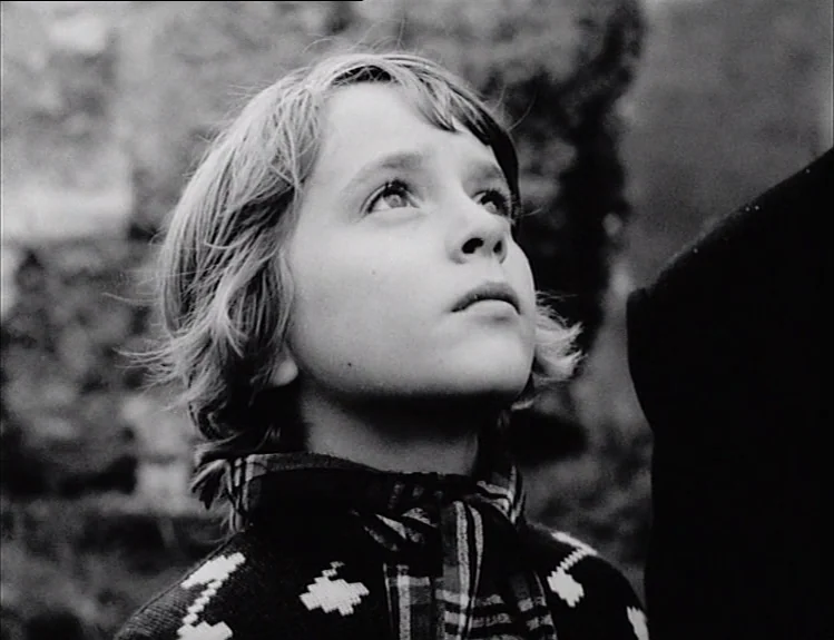 The Arrival of Joachim Stiller (1976) movie still: closeup — A young child stands in an outdoor environment with soft natural lighting. The boy…