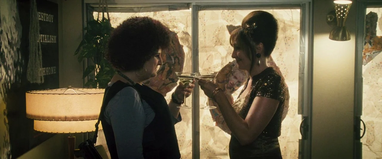 Southland Tales (2006) movie still: medium — An interior space features a floor lamp and a window covered with taped posters. Two women stand in…