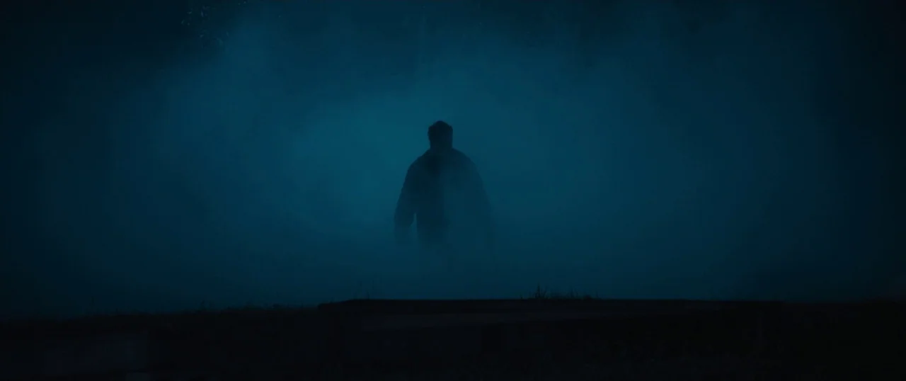 Final Girls (2015) movie still: wide — A dark, hazy environment is illuminated from behind by a cold, diffused light source. A solitary figure…
