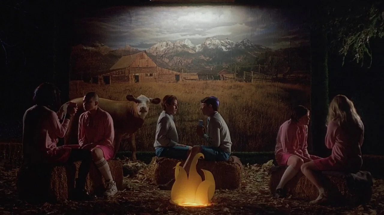 But I’m A Cheerleader (1999) movie still: wide — A theatrical stage set features a large backdrop of a mountain range and barn. Six individuals sit…