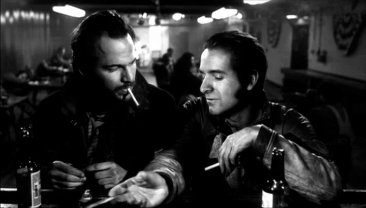 The American Astronaut (2001) movie still: medium — A dimly lit bar at night featuring two men sitting together at the counter. The men interact…