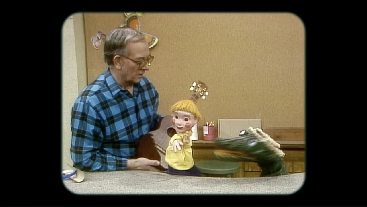 Mr. Dressup: The Magic of Make Believe (2023) movie still: medium — A television studio workshop featuring wooden panels and colorful puppet…