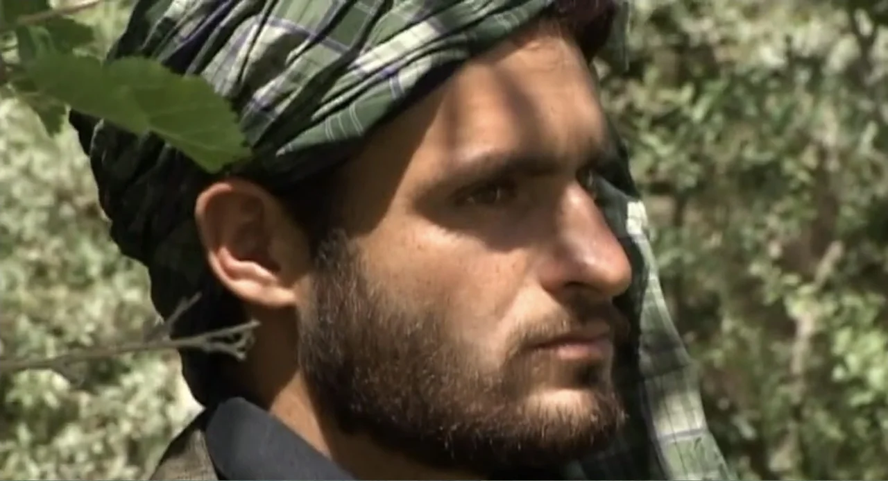 Afghanistan's Opium Trail (2007) movie still: closeup — A man stands outdoors near dense foliage with leaves visible in the foreground. He looks…