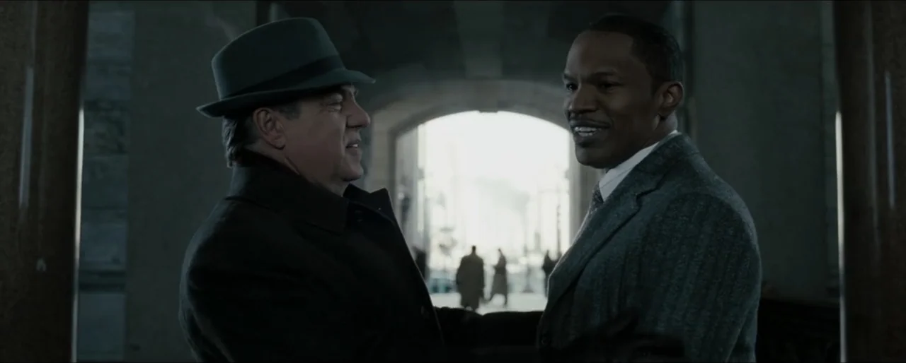 Law Abiding Citizen (2009) movie still: medium — Two men stand within a stone building entranceway that opens to a bright city street. The older man…
