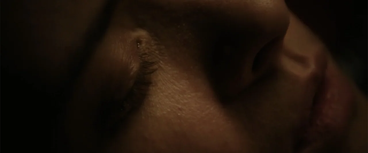 Freud's Last Session (2023) movie still: closeup — A dimly lit interior space with a subject resting in darkness. A person with closed eyes is…