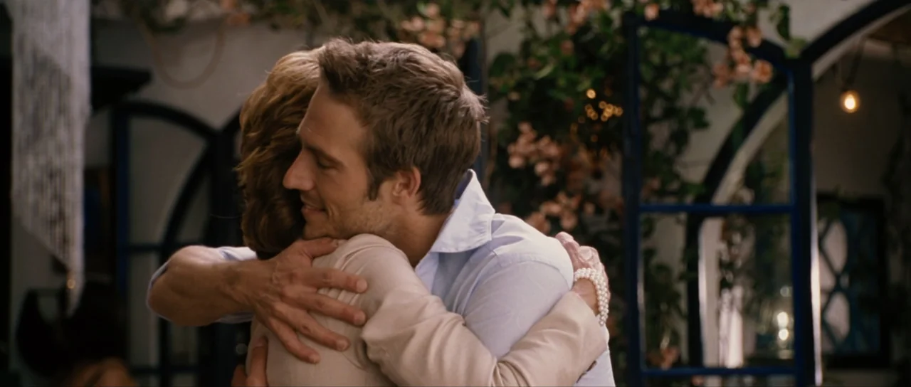 Monster-in-Law (2005) movie still: medium — A light-filled interior space with climbing vines visible through an open window frame. A man in a blue…