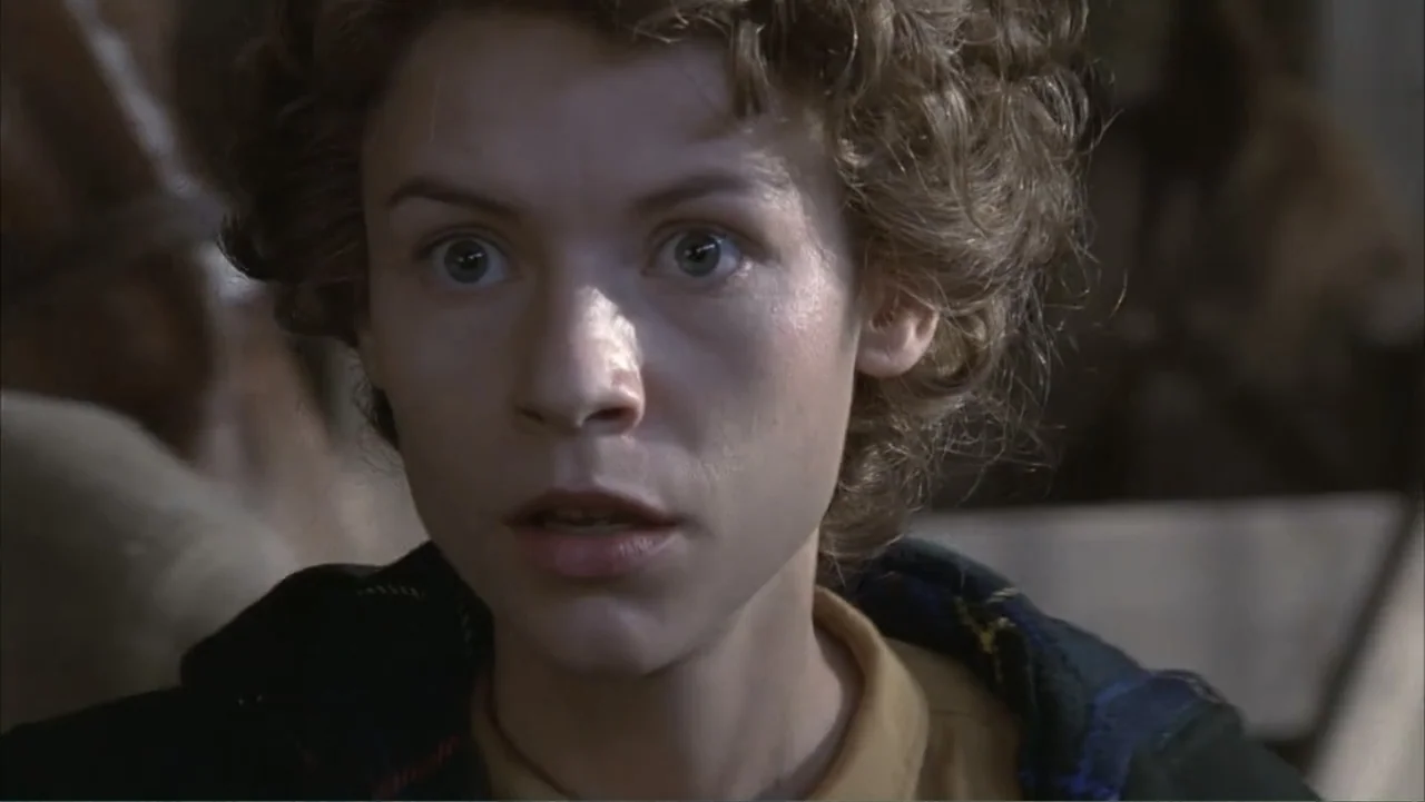 Temple Grandin (2010) movie still: closeup — A dimly lit wooden interior space with blurred structures in the background. A young woman with short…