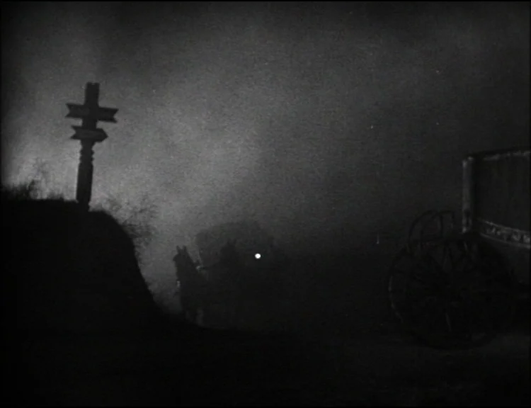 Dracula (1931) movie still: wide — A dark, fog-covered dirt road at night with an old-fashioned signpost and carriage. The frame centers on the…