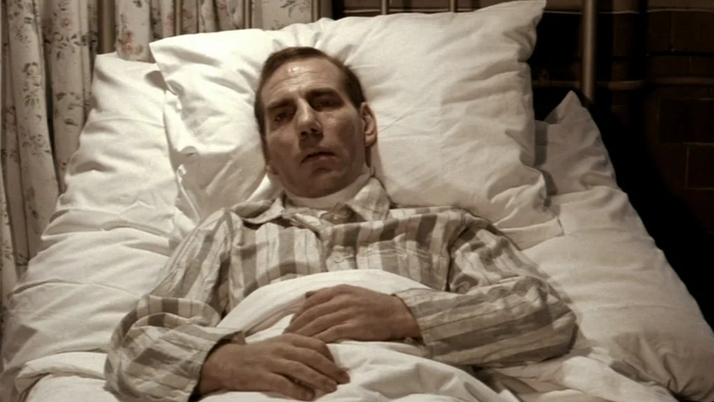 Distant Voices, Still Lives (1988) movie still: medium — A man lies flat on a hospital bed with crisp white linens. He is resting with his hands…