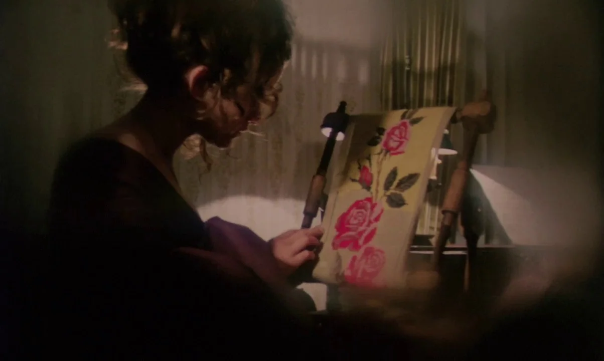 Kamouraska (1973) movie still: medium — A dimly lit room features a woman sitting at an embroidery stand at night. She carefully works on a piece of…