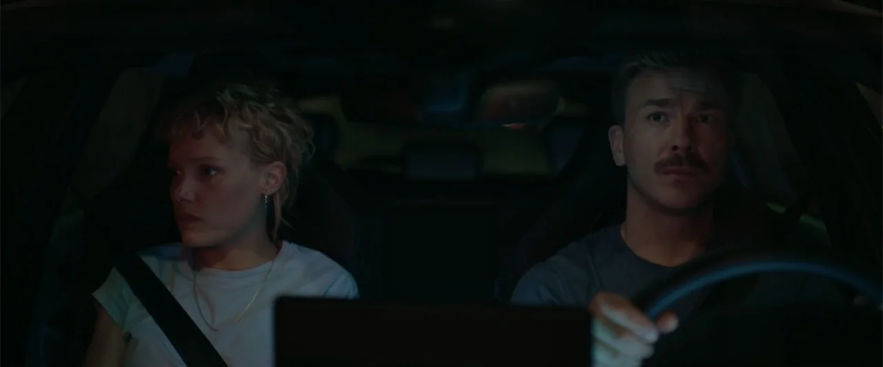Peacock (2010) movie still: medium — The interior of a car at night shows two passengers in the front seats. A man drives while a woman looks ahead…
